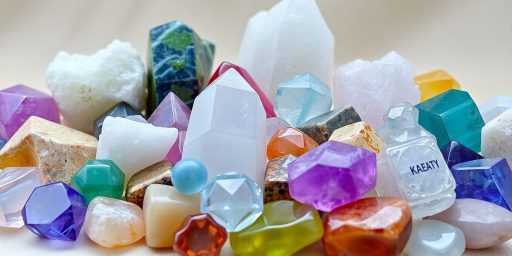Varie pietre cristalline colorate su sfondo neutro.